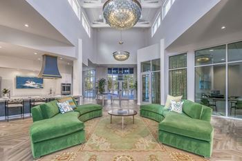 A living room with green couches and a large chandelier.